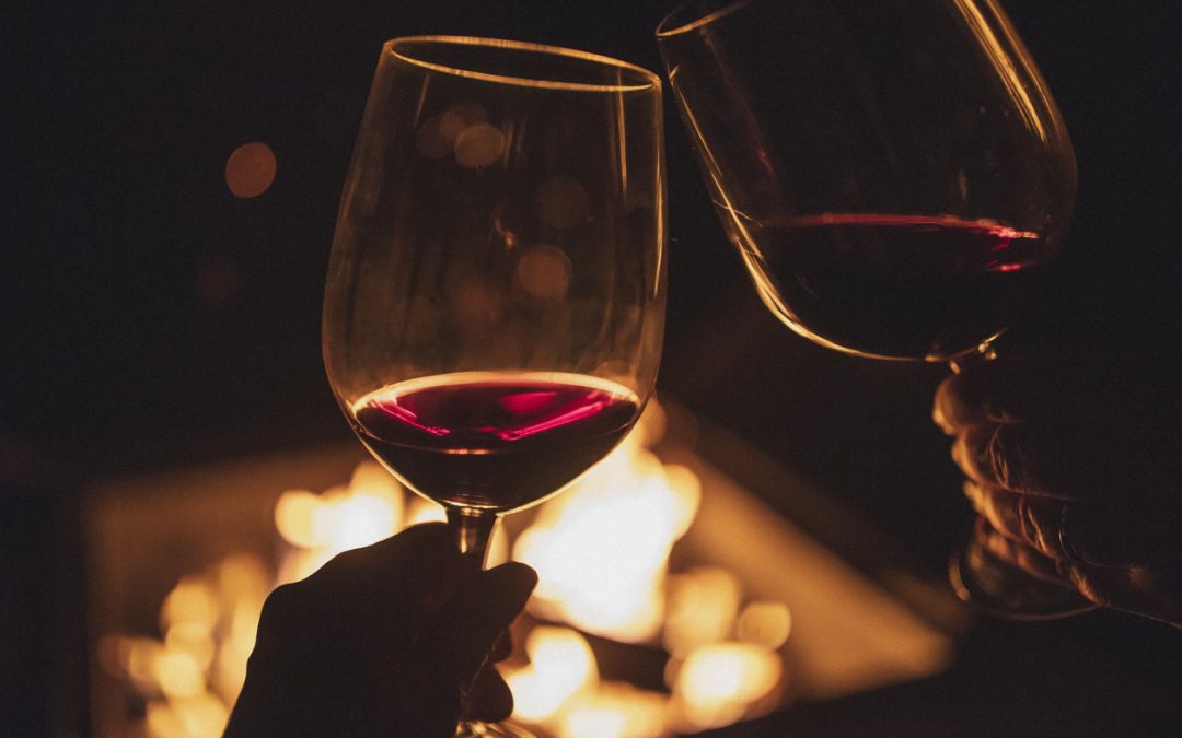 Cheering Couple, Each Holding A Glass Of Wine In Front Of A Fire Pit.