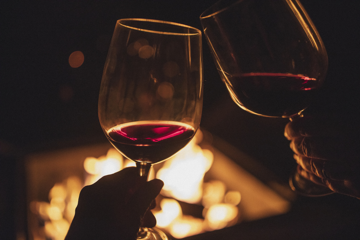 Cheering Couple, Each Holding A Glass Of Wine In Front Of A Fire Pit. Cheering Couple, Each Holding A Glass Of Wine In Front Of A Fire Pit.